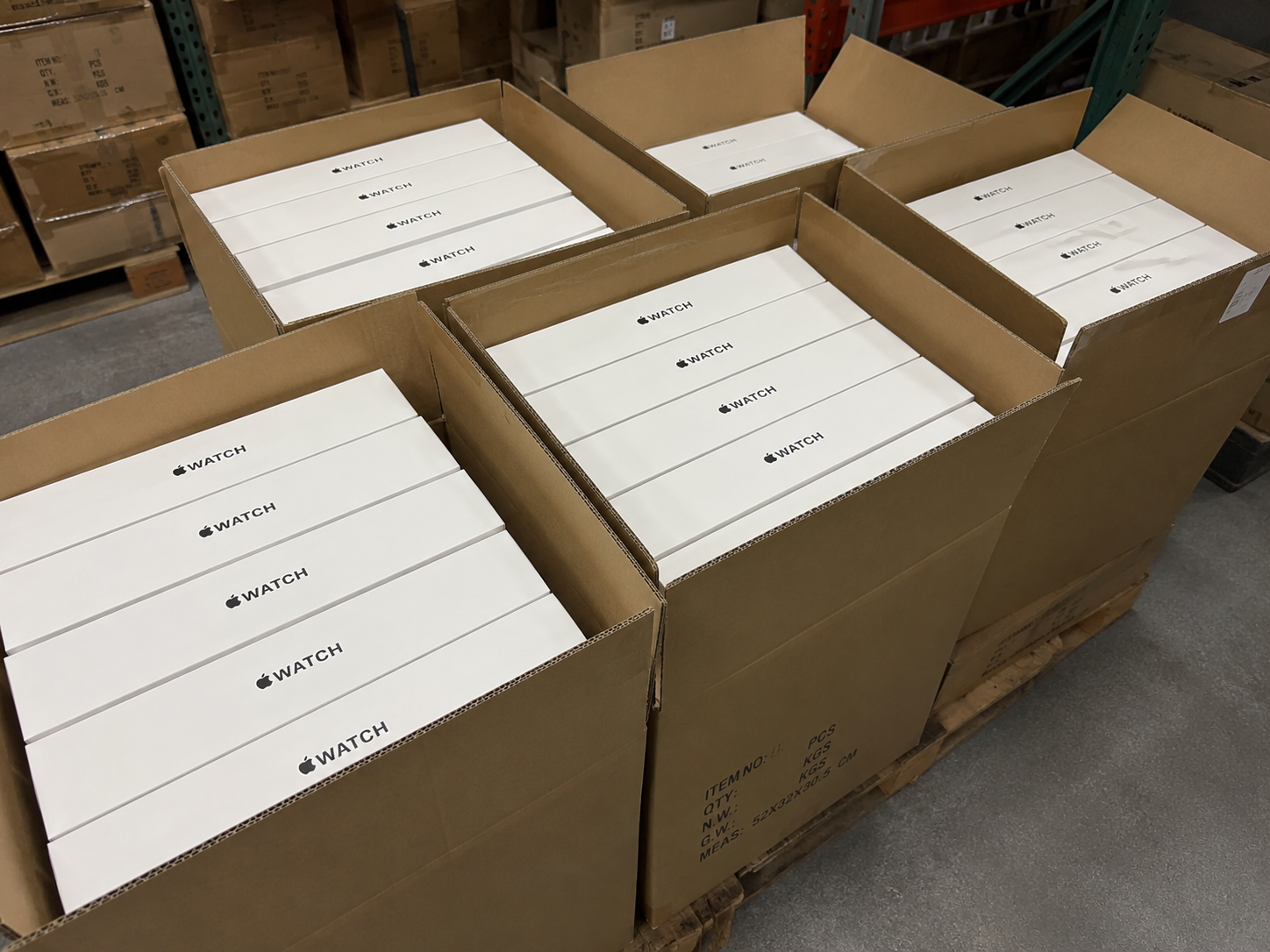 Stacked retail boxes of premium Apple products on a warehouse pallet